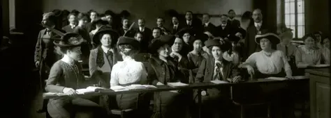 Femmes assises dans une salle de cours, hommes debout au fond.